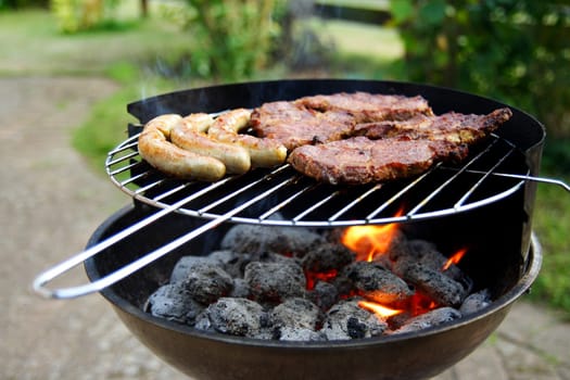 Grill with grilled meat and bratwurst in the garden
