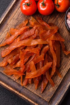 Jerky, dried turkey meat with salt and spices on a dark concrete background