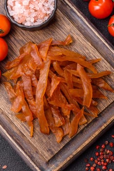 Jerky, dried turkey meat with salt and spices on a dark concrete background