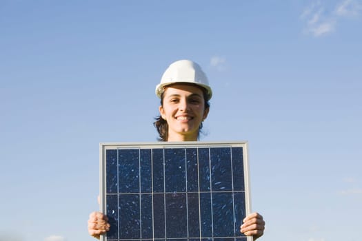 Woman holding a solar panel in front of a blah