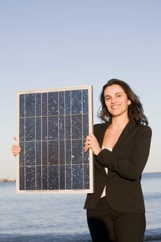 Woman holding a solar panel in front of a blah