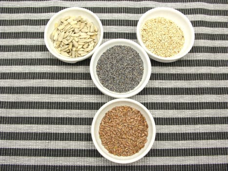 Four bowls with different seeds on a striped background