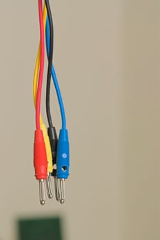 A tangle of interwoven male connectors against a wall and a circuit in the backg