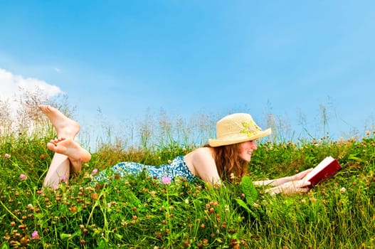 Young girl reading book in meadow
