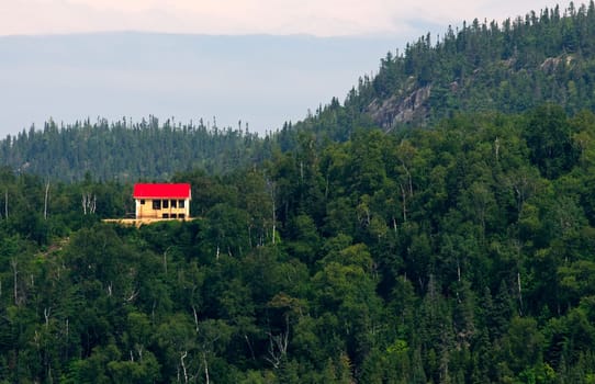 Small house with red roof on the edge of the forest
