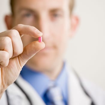 Young male doctor holding medication. Square format.