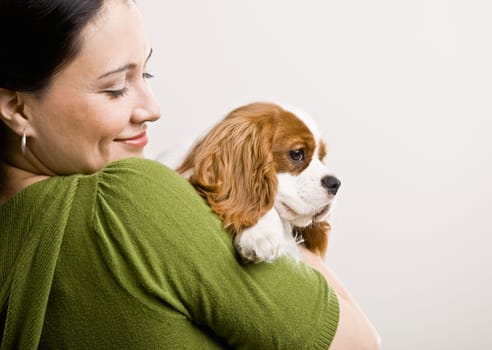Adult female holding puppy. Horizontally framed shot.