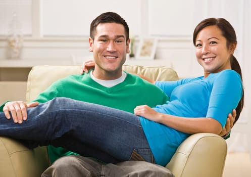 Attractive Asian Couple relaxing together on their living room couch. Horizontally framed photo.