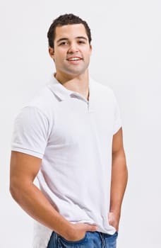 An attractive man posing in blue jeans and a polo shirt. He is smiling directly at the camera. Vertically framed shot.