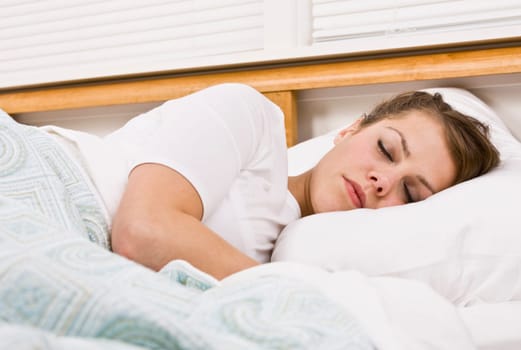 A beautiful young woman is sleeping in her bed. Horizontally framed shot.