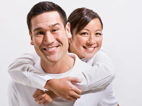 An attractive young couple posing together. They are smiling directly at the camera. Horizontally framed shot.