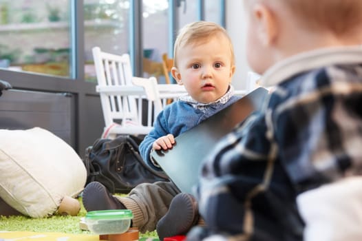 Two babies on the floor playing. Horizontally framed shot.