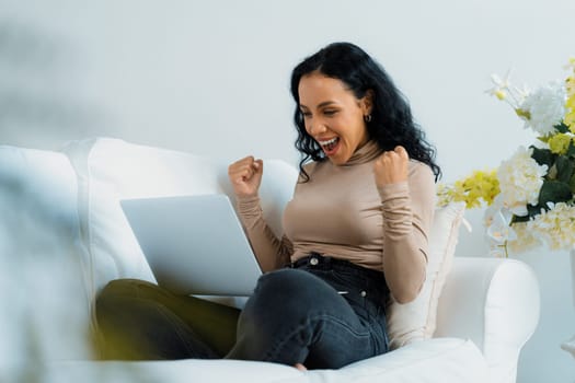 Successful African-American businesswoman feel happy at crucial work on laptop computer while sitting on sofa couch at home