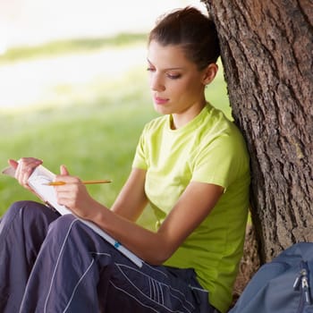 young woman studying outdoors and leaning on tree. Copy space