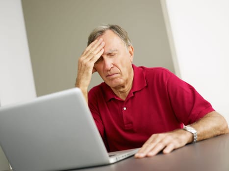 Senior man having headache while using laptop. Copy space