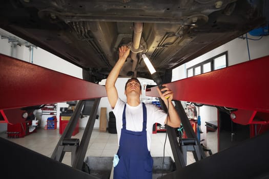 mechanic standing under car engine and holding lamp. Copy space
