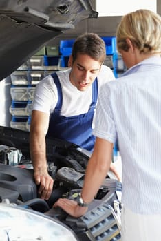 mechanic talking with female client in auto repair shop.