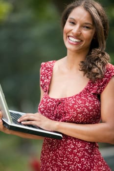 Young woman using laptop in outdoor setting. Vertically framed shot.