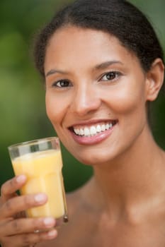 Closeup of young woman drinking orange juice in outdoor setting. Vertically framed shot.