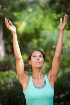 Young woman with arms raised in outdoor setting. Vertically framed shot.