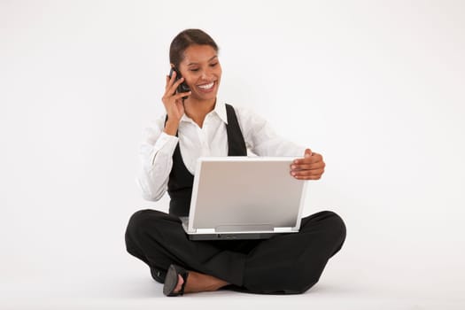 Young woman sitting on floor using laptop and cell phone. Horizontally format.