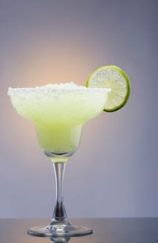 Frozen Margarita mixed drink with lime slice on plain background close up