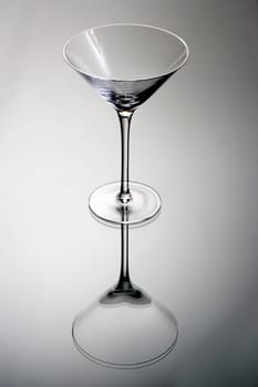 Empty martini glass on a grey background with reflection