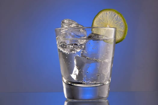 Club Soda on the rocks with lime slice garnish on plain background