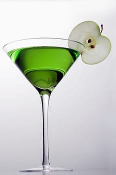 Apple Martini mixed drink with apple slice garnish on grey background