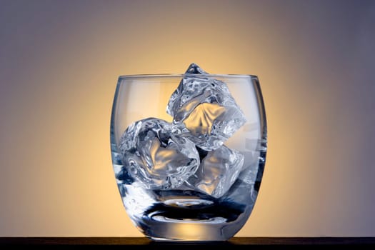 Empty Old Fashioned glass with ice cubes on plain background
