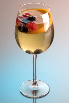 Glass of white wine sangria on grey background with reflection