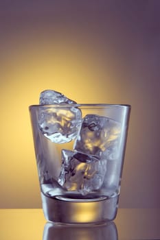Glass with ice cubes on plain background