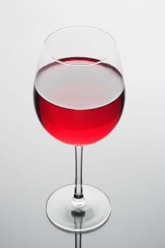 Red wine in a glass on a plain background with reflection