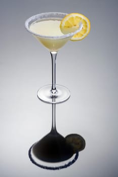 Lemon Drop mixed drink with lemonslice garnish on grey background with reflection