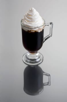 Irish Coffee mixed drink on grey background with reflection