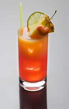 Mai Tai mixed drink with fruit garnish on a plain grey background with reflection