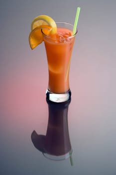 Zombie mixed drink with orange and lemon garnish on grey background with reflection