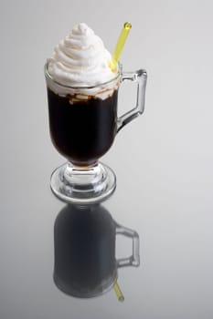 Irish Coffee mixed drink on grey background with reflection