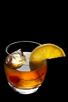 Old Fashioned mixed drink with orange clice and cherry garnish on a black background