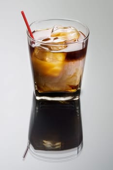 White Russian mixed drink on a grey background with reflection
