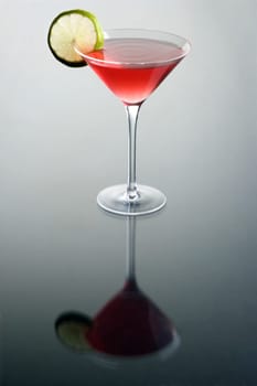 Cosmopolitan cocktail with lime slice on grey background