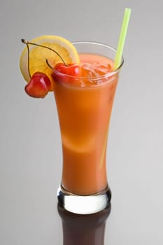 Zombie mixed drink with cherry and lemon garnish on grey background with reflection