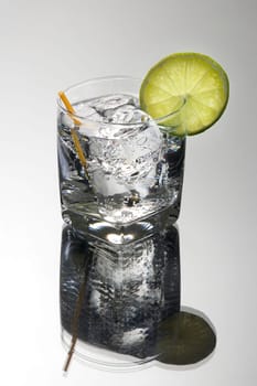 Club soda or Gin or Vodka and tonic mixed drink with lime slice garnish on a grey background