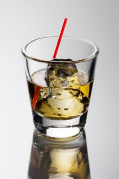 Scotch on the rocks on a grey background with reflection