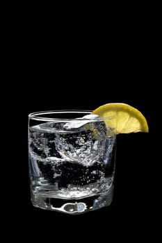 Club soda or Vodka / Gin and tonic mixed drink with lemon slice on a black background
