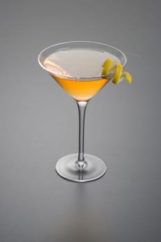 Manhattan cocktail with lemon peel garnish close up on grey background