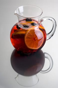 Pitcher of Red Sangria with aranges and blackberries on grey background close up