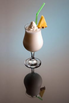 Pina Colada mixed drink with pineapple garnish on plain background with reflection