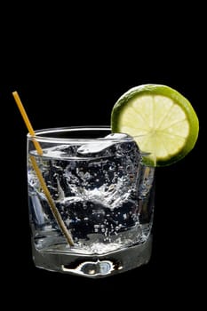 Club soda or Gin or Vodka and tonic with lime slice garnish on a black background