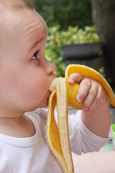 child eat yellow banana in outdoors